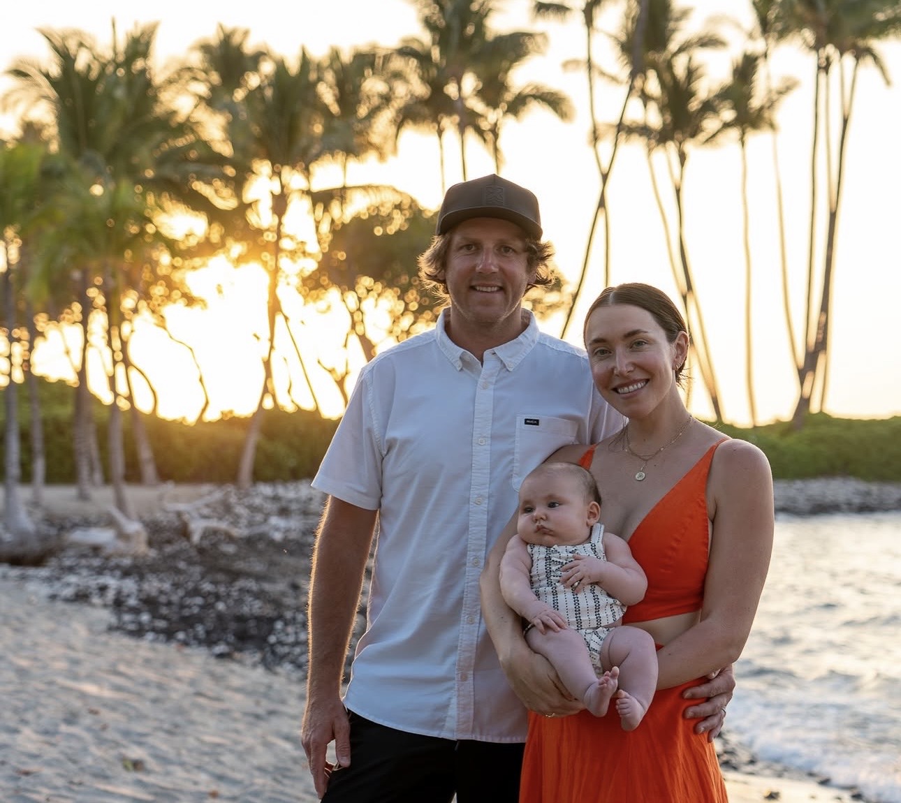 Family posing on a beach at sunset.
