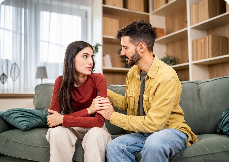 Man comforting woman on a couch.