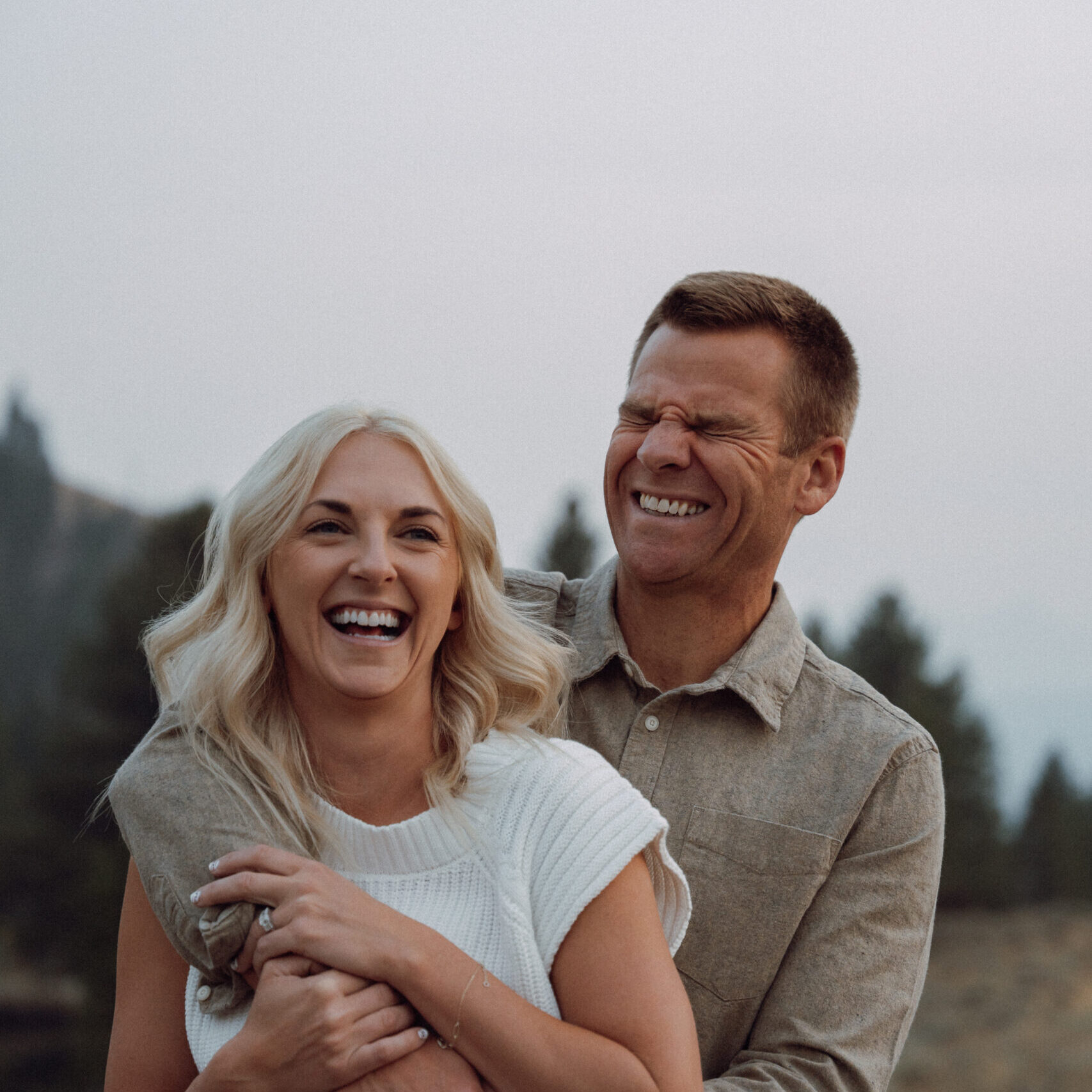 Couple laughing outdoors during twilight.